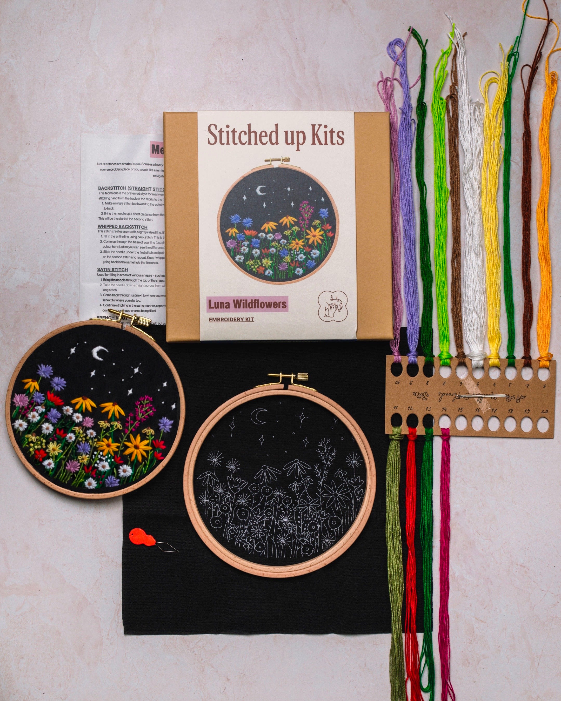 Embroidery kit with completed hoop art, thread set, and packaging on a neutral background