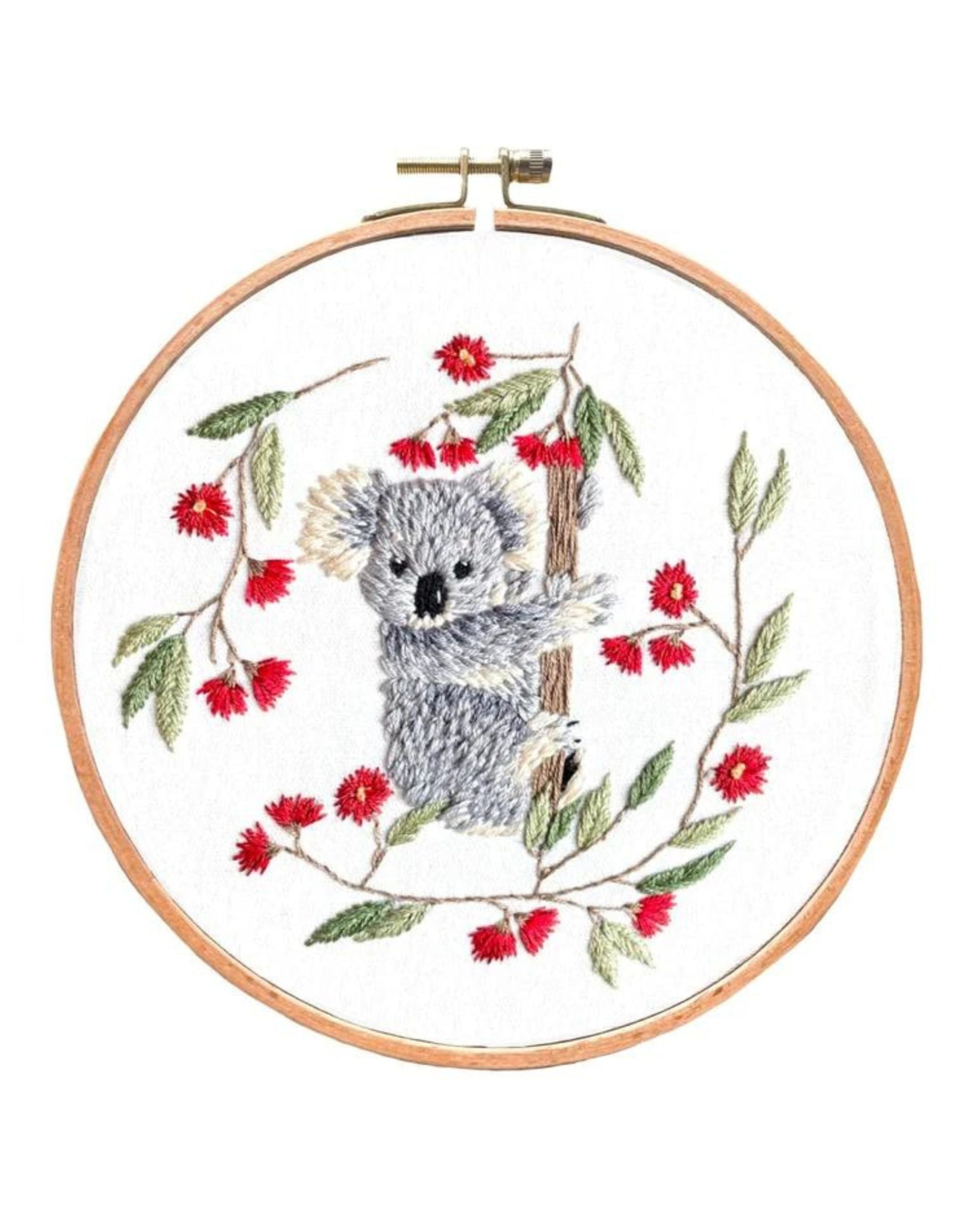 Baby Koala embroidery artwork featuring gray koala surrounded by red flowers and green leaves in wooden hoop on white fabric