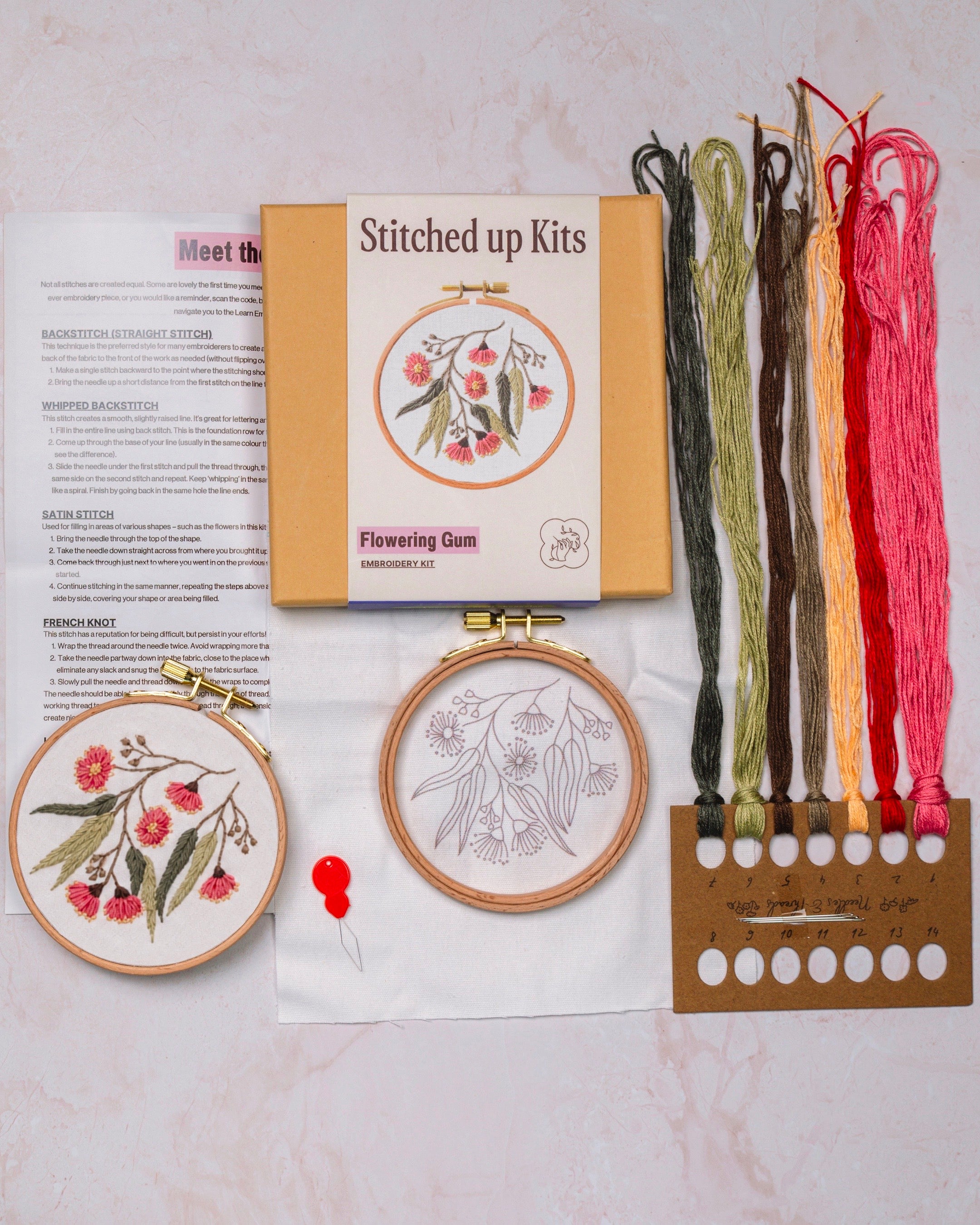 Embroidery kit with floral patterns, threads, and a cardboard box on a light background