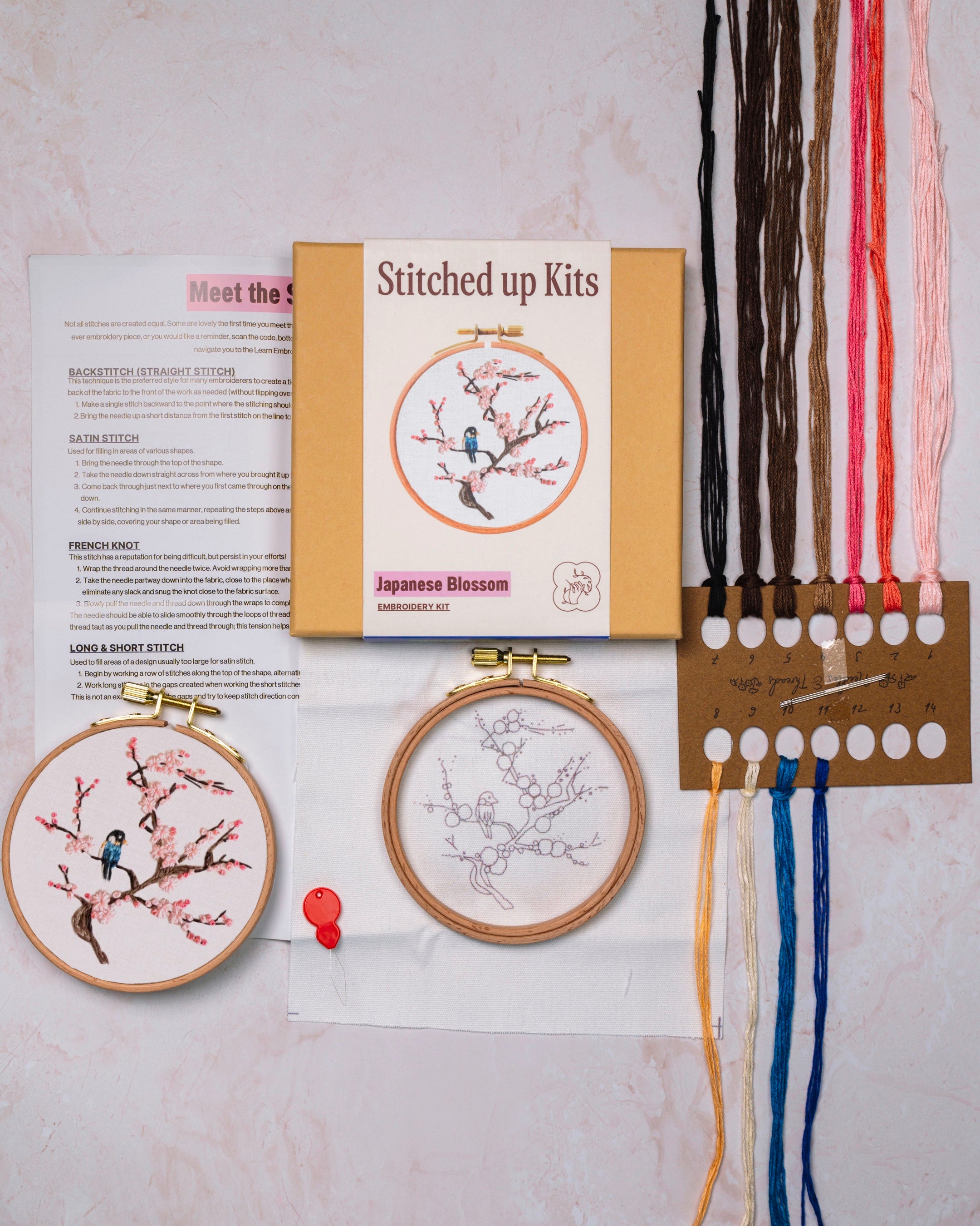 Embroidery kit flat lay with box, threads, embroidery hoop and needles