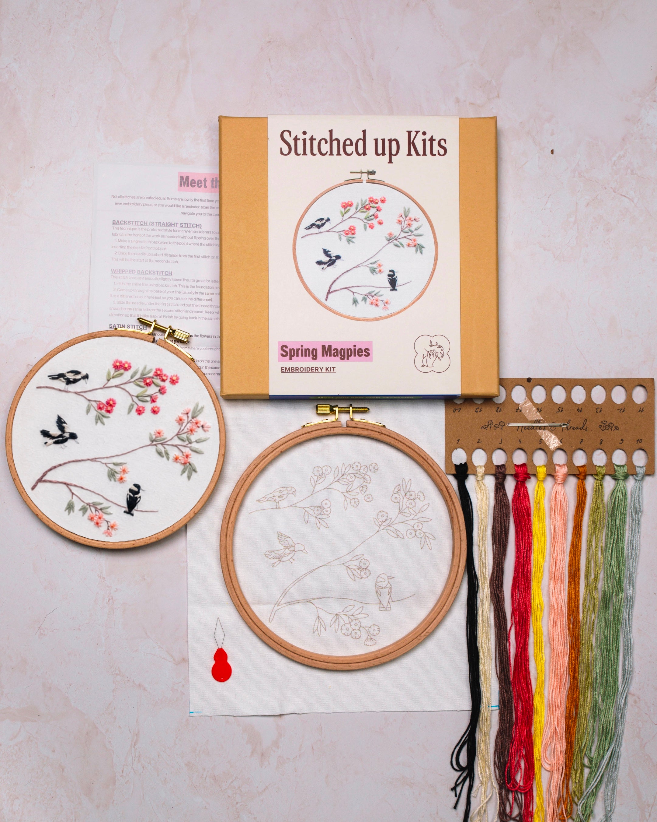 Embroidery kit with hoops, threads, and a pattern book on a light background