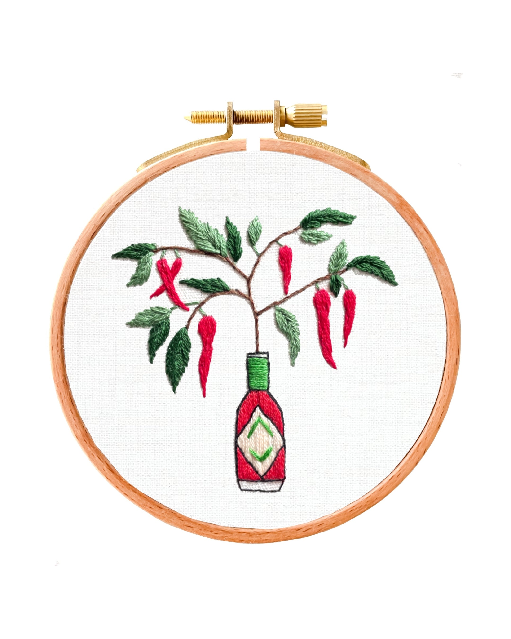 Embroidery hoop with a embroidered design of a bottle and red peppers on a white background