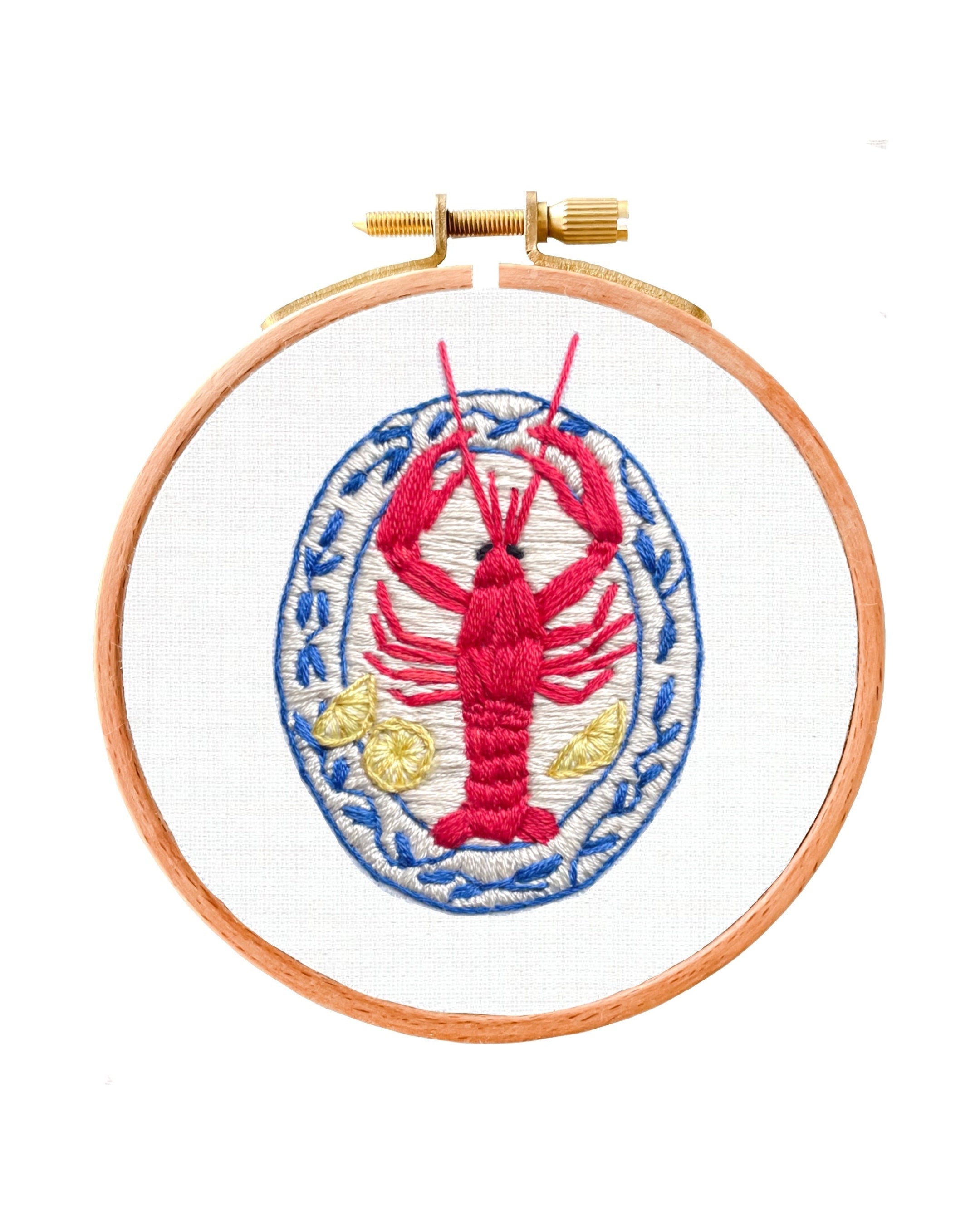 Embroidery hoop with a red lobster design on a white background